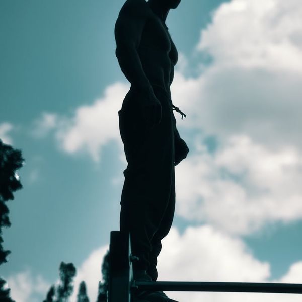Focused man during a complex bodyweight exercise, showing balance and strength.